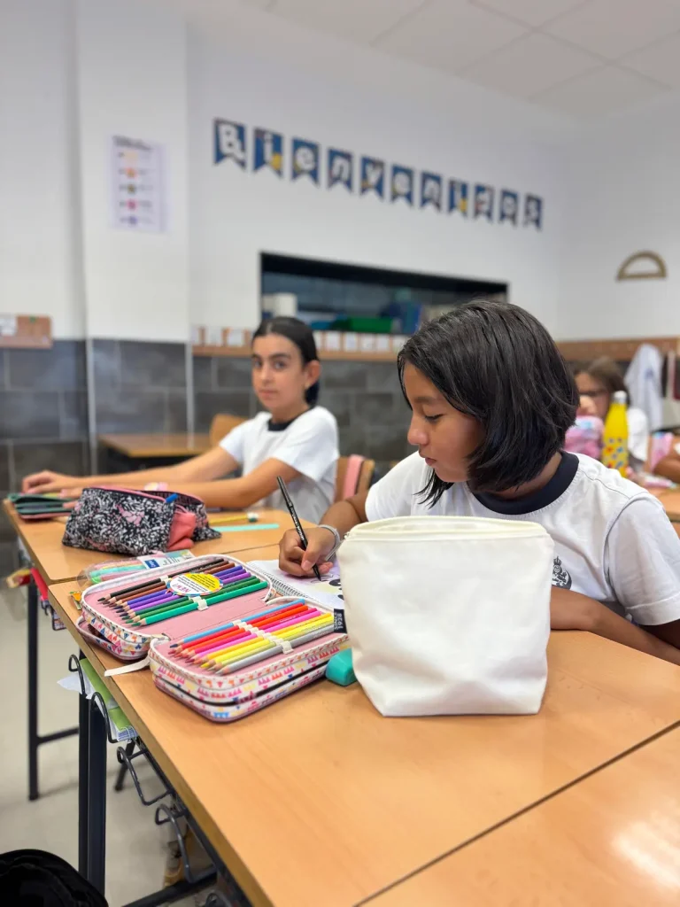 Alumnas en su pupitre con estuches y material escolar nuevo para el curso 2026/2027