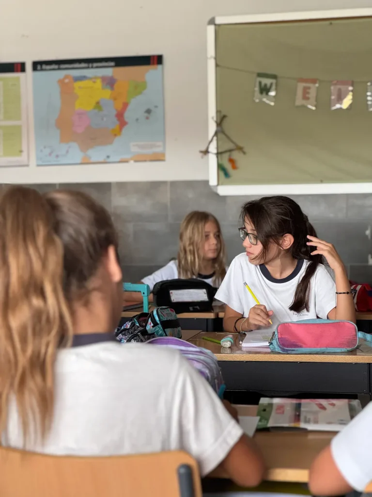 Alumnas en el aula con el mapa de las comunidades autónomas de España en la pared
